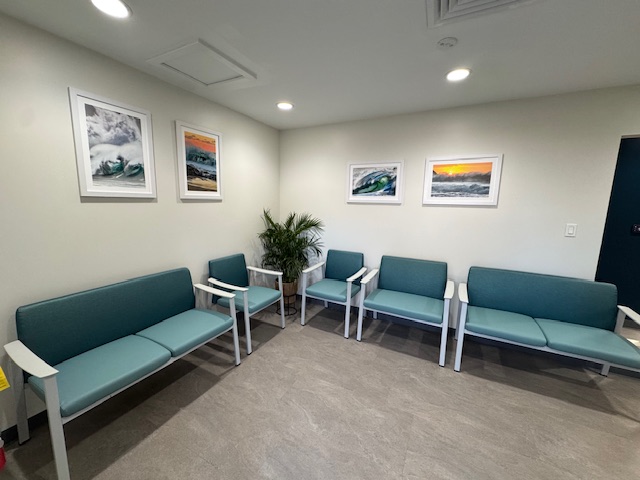 Dental clinic waiting room with teal seating, framed artwork, and plants.