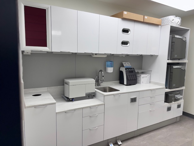 Dental sterilization room with sinks, cabinets, and modern cleaning equipment.